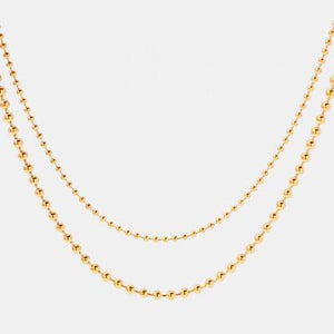 a gold ball chain necklace on a white background