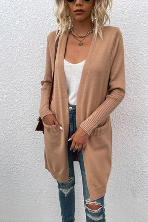 a woman wearing a tan cardigan sweater and ripped jeans