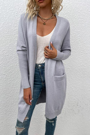 a woman wearing a grey cardigan sweater and ripped jeans