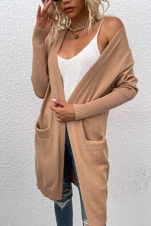 a woman wearing a tan cardigan sweater and ripped jeans