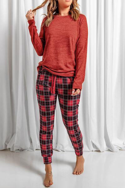 a woman wearing a red sweater and plaid pants