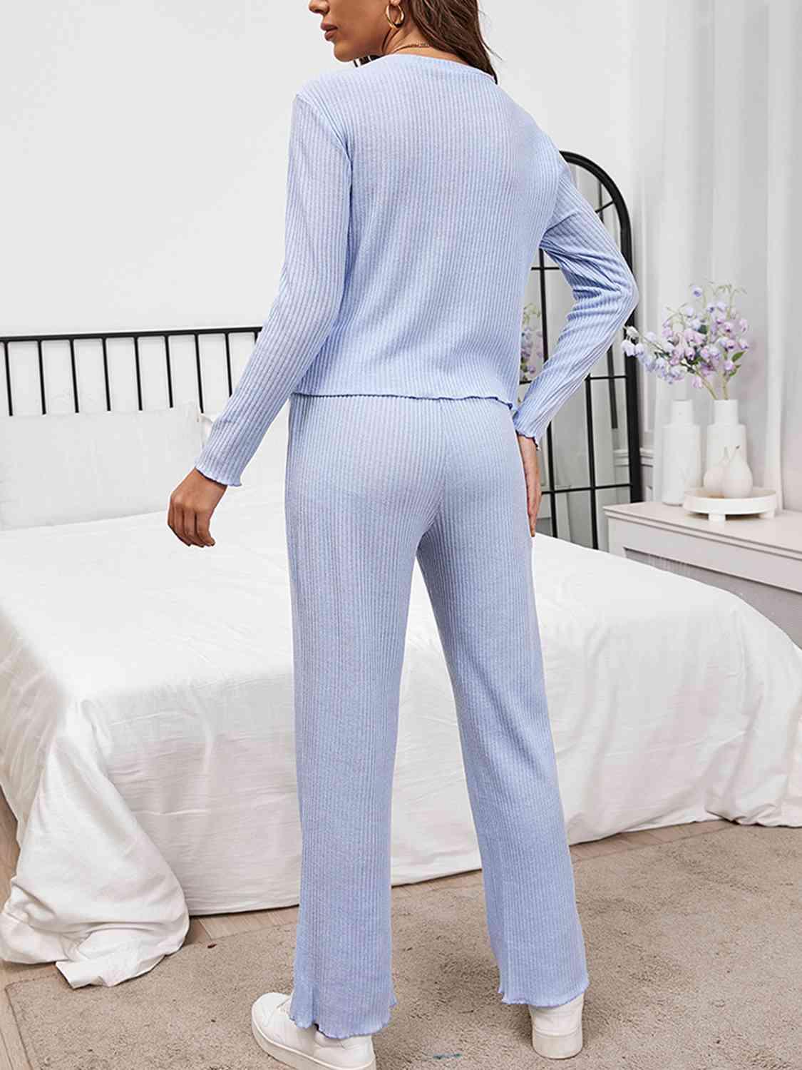 a woman in a blue sweater and pants standing in front of a bed