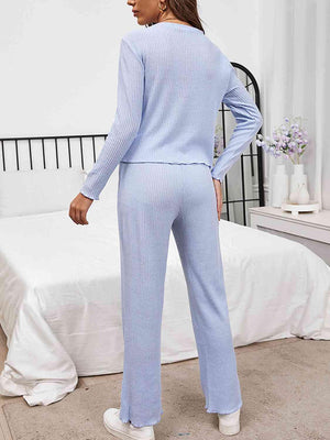 a woman in a blue sweater and pants standing in front of a bed