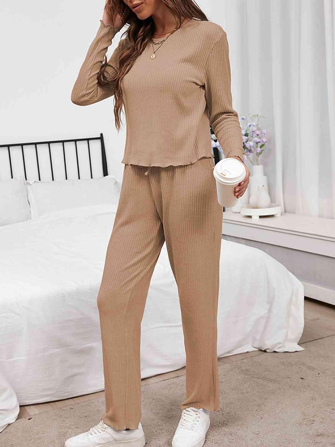 a woman standing in a bedroom wearing a tan outfit
