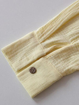 a button on a yellow shirt on a white surface