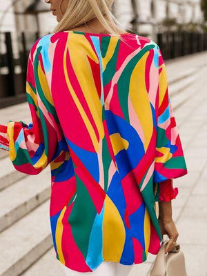 a woman wearing a colorful top and white pants