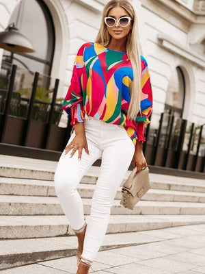 a woman wearing white pants and a colorful top