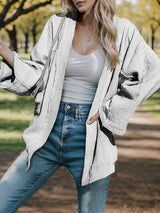 a woman standing in a park wearing a white sweater and jeans