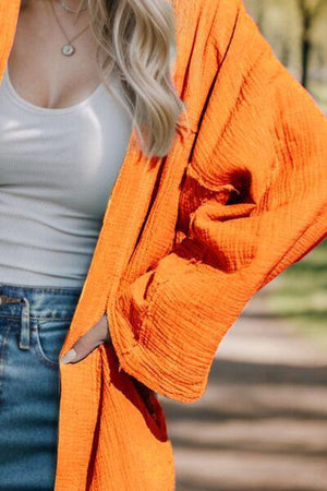 a woman wearing an orange cardigan and jeans