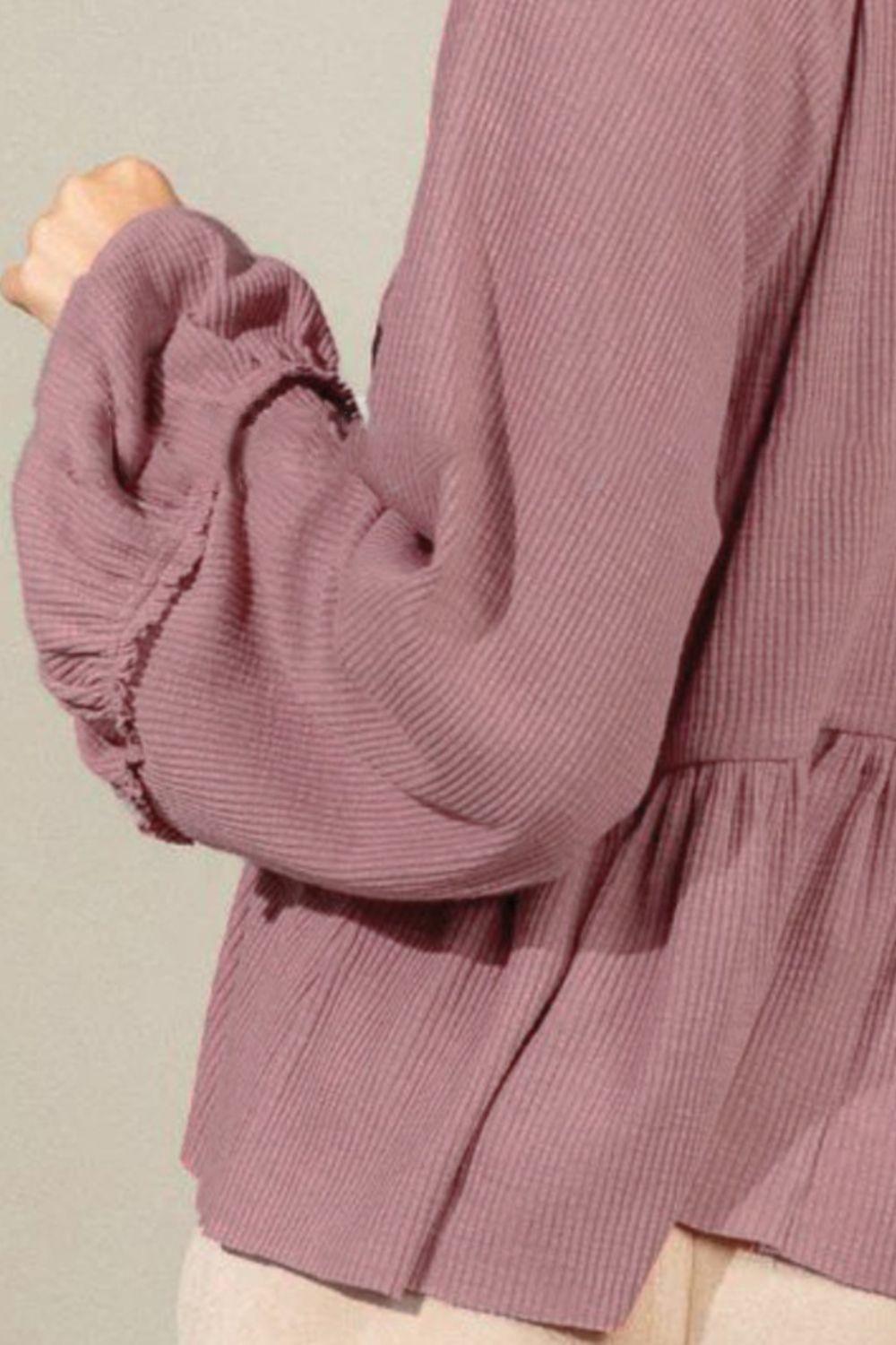 a woman wearing a purple top with ruffled sleeves