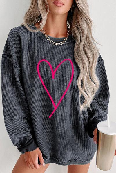 a woman wearing a grey sweater with a pink heart on it