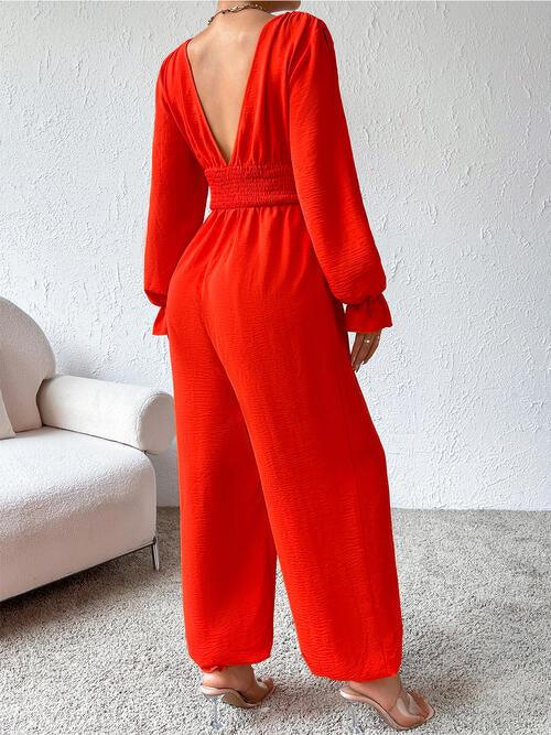 a woman in a red jumpsuit standing in a room