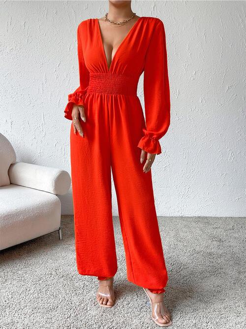 a woman in a red jumpsuit standing in front of a white couch