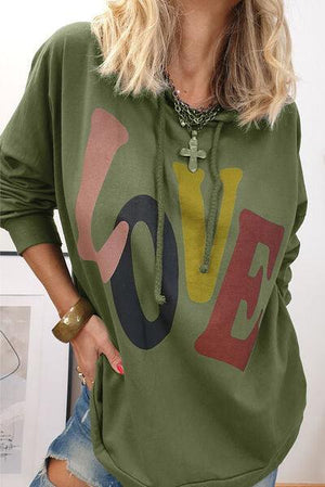 a woman wearing a green sweatshirt with the word love on it