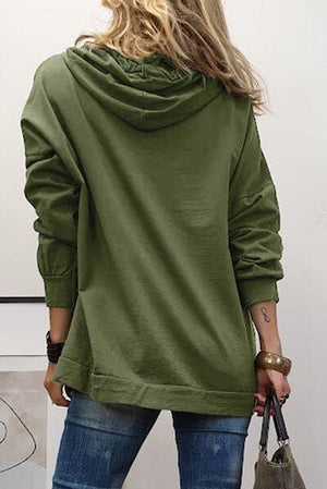 a woman in a green hoodie holding a handbag