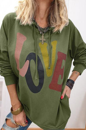 a woman wearing a green sweatshirt with the word love on it