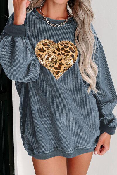 a woman wearing a grey sweater with a leopard heart on it