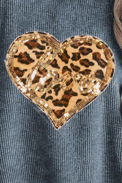 a woman wearing a blue sweater and a leopard print heart brooch