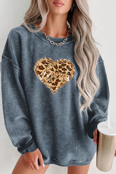 a woman wearing a blue sweater with a leopard heart on it