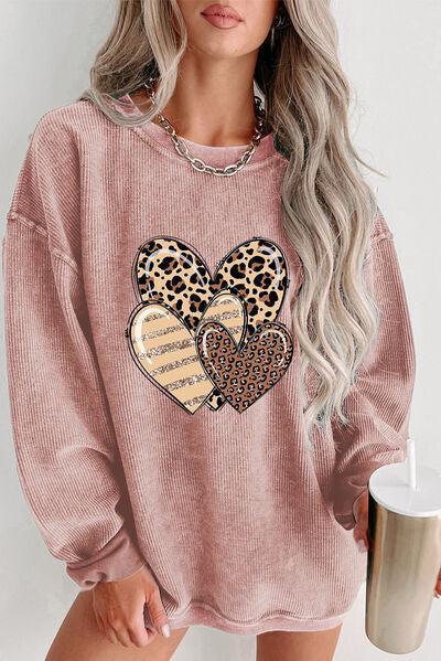 a woman wearing a pink sweater with a leopard heart on it