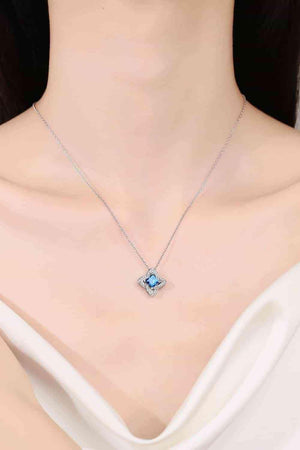 a woman wearing a necklace with a blue stone