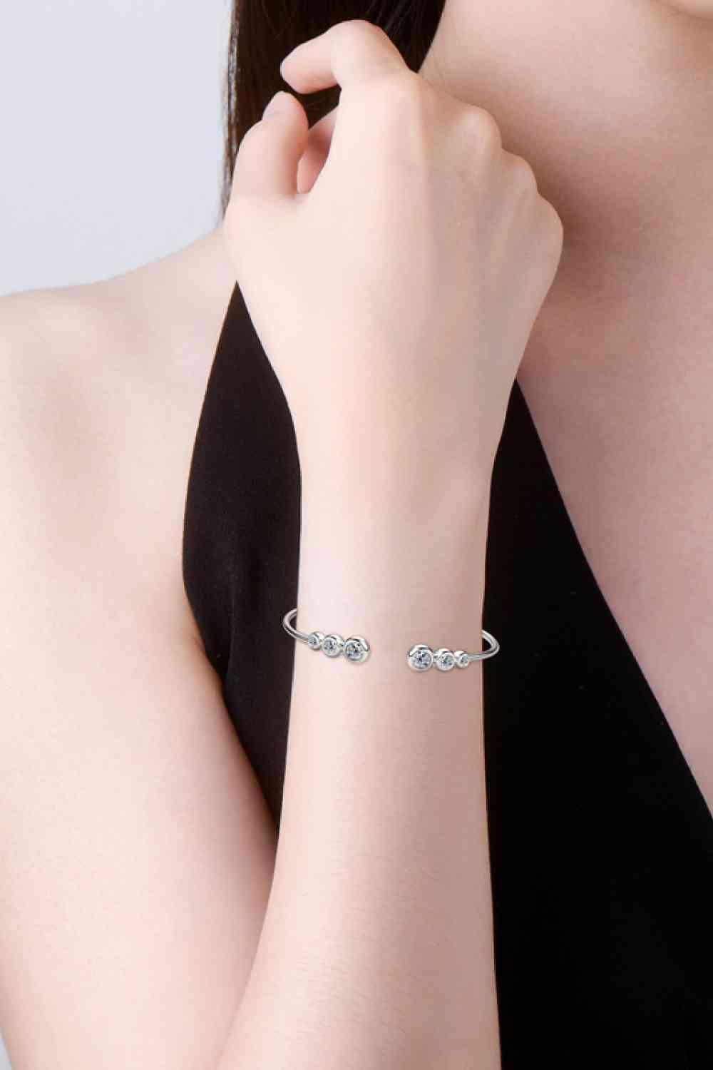 a woman wearing a silver bracelet with two hearts on it