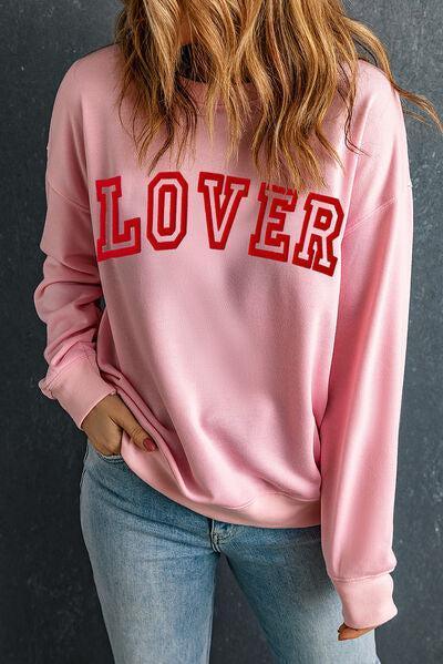 a woman wearing a pink sweatshirt with the word lover on it
