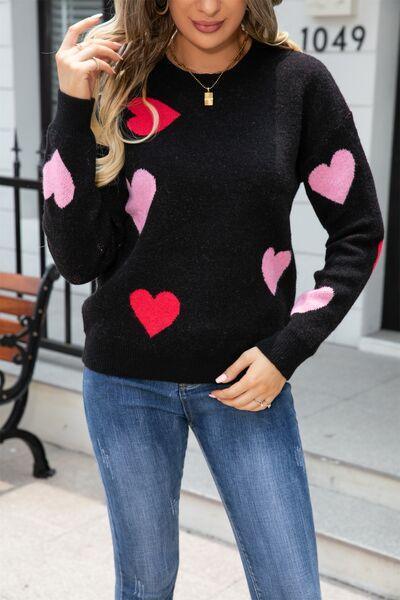 a woman wearing a black sweater with pink hearts on it