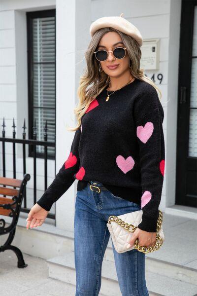 a woman wearing jeans and a sweater with hearts on it