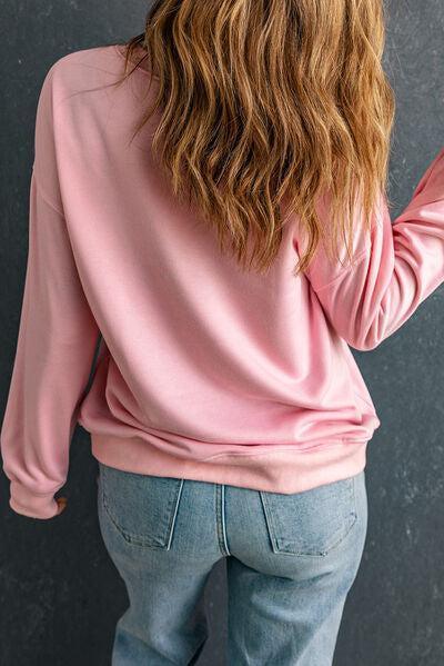 a woman wearing a pink sweatshirt and jeans