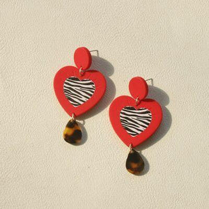 a pair of earrings with a heart and a zebra print