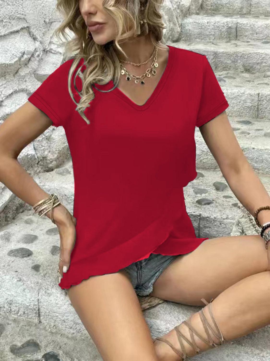 a woman sitting on the ground wearing a red shirt