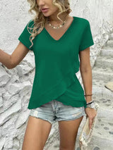 a woman wearing a green top and denim shorts