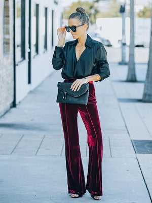 a woman in a black top and red velvet pants