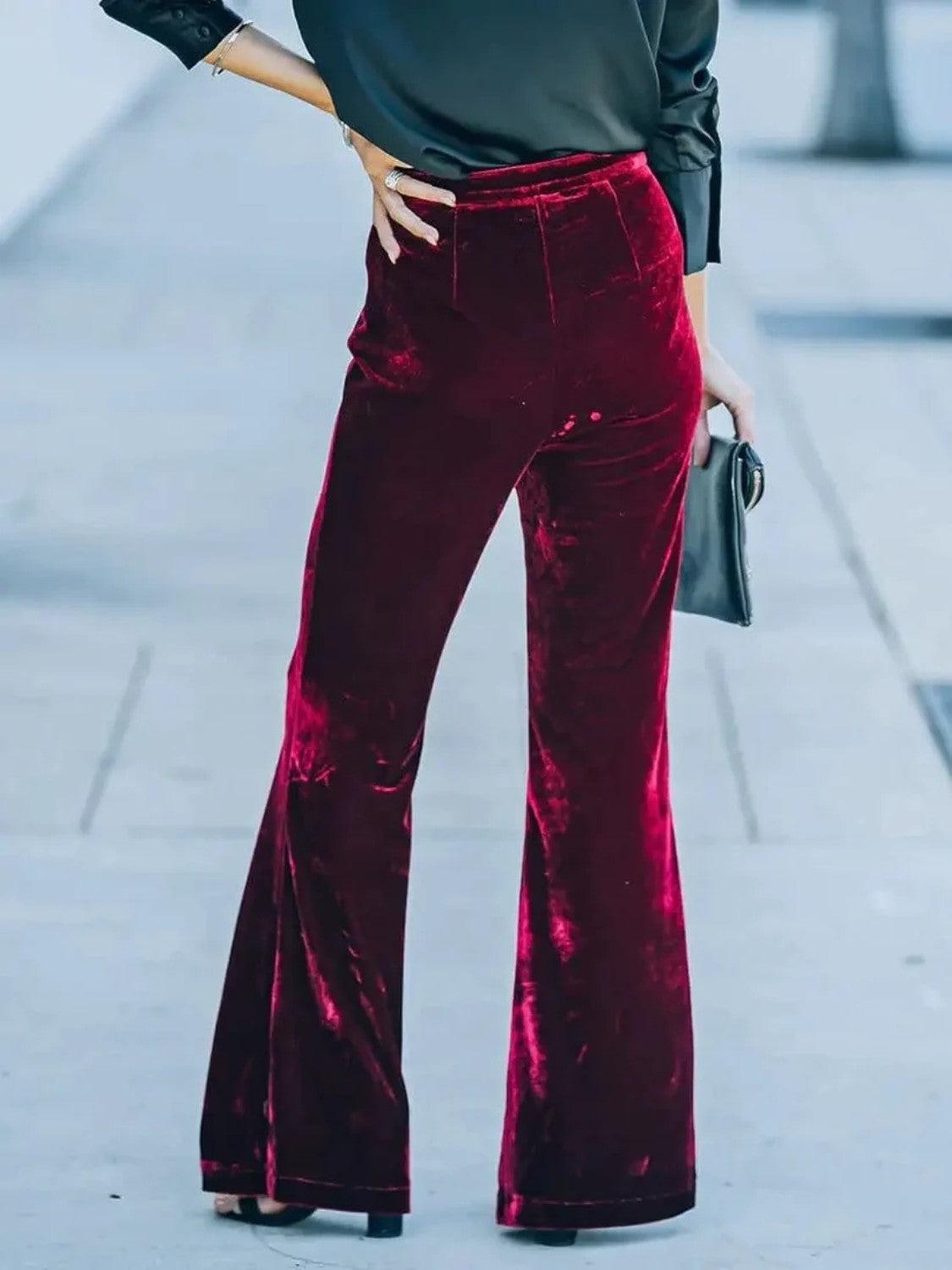 a woman in a black top and red velvet pants