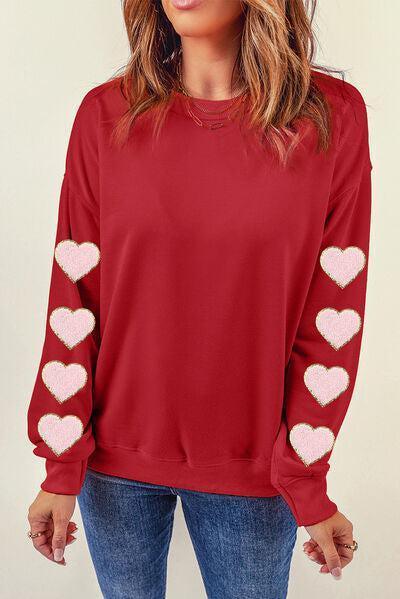 a woman wearing a red sweater with hearts on it
