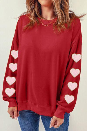 a woman wearing a red sweater with hearts on it