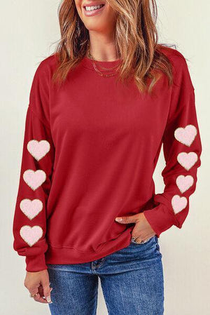 a woman wearing a red sweater with hearts on it