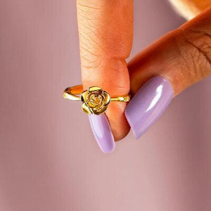 a woman's hand holding a ring with a rose on it