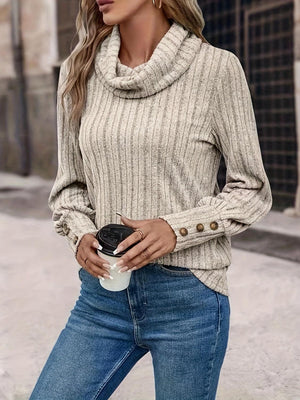 a woman in a sweater and jeans holding a cup of coffee