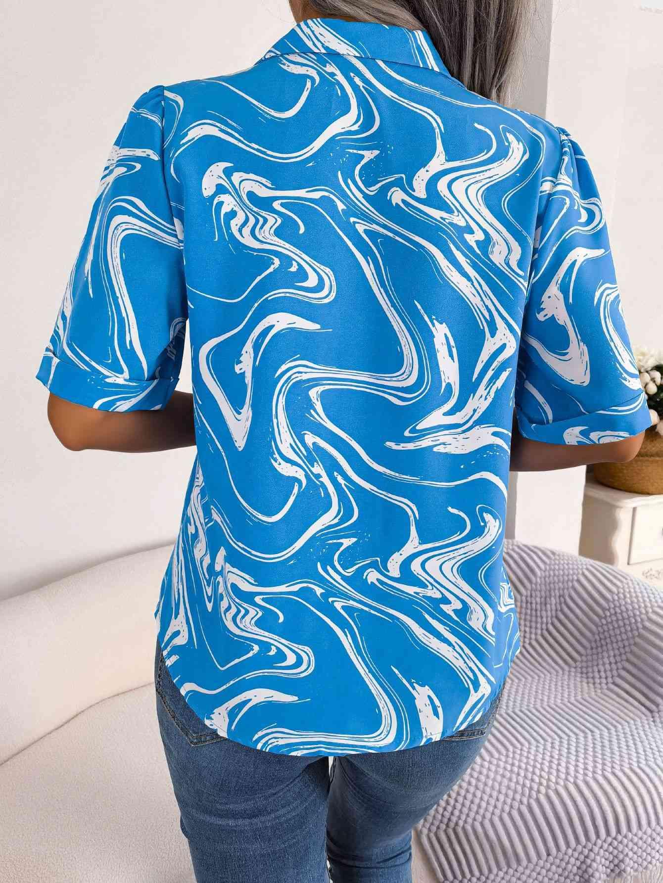 a woman wearing a blue shirt with white swirls on it