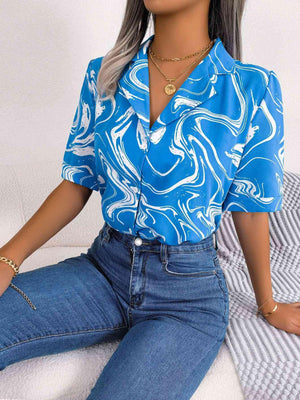 a woman sitting on a bed wearing a blue shirt and jeans