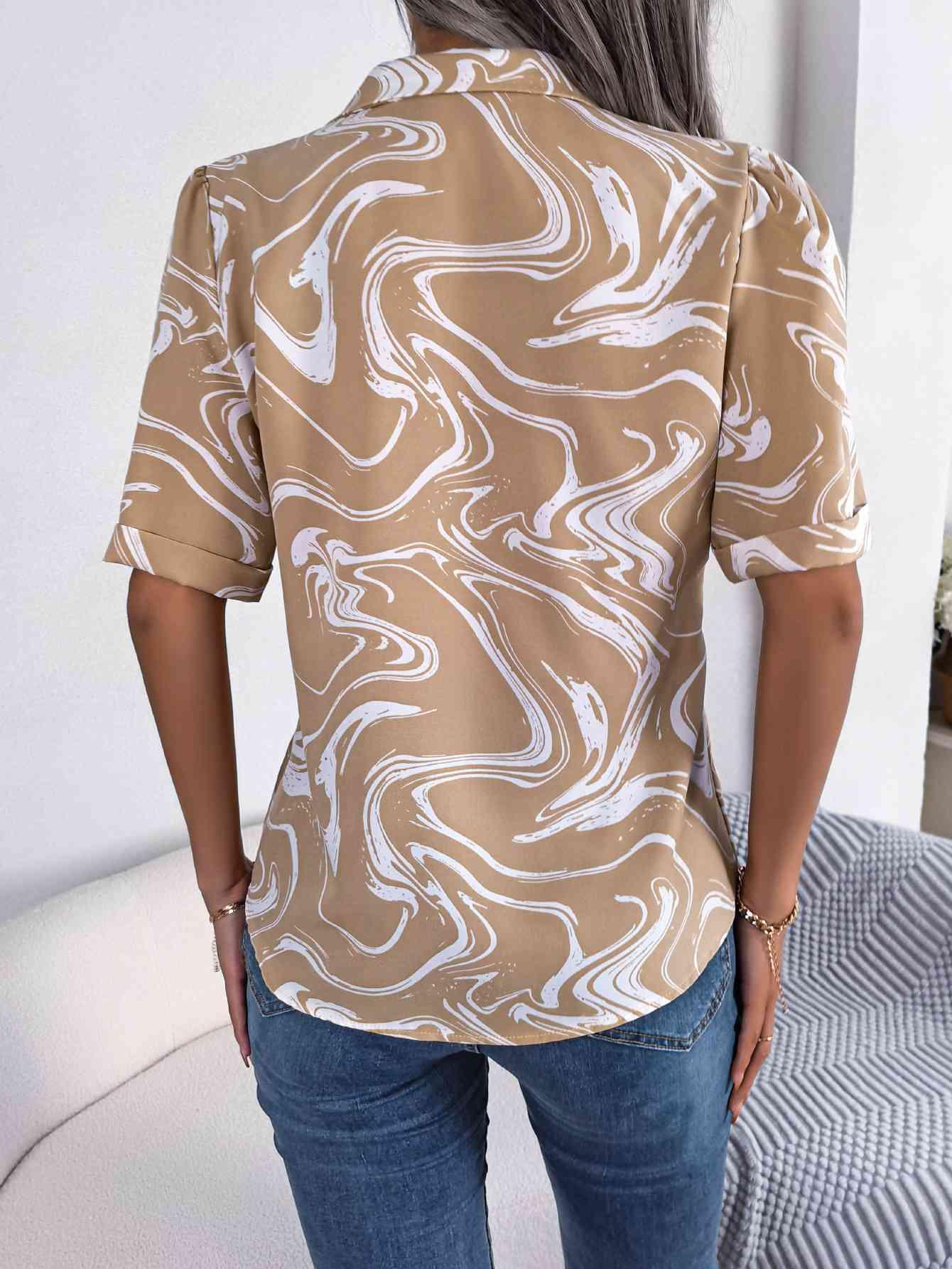 a woman wearing a tan shirt with white swirls on it