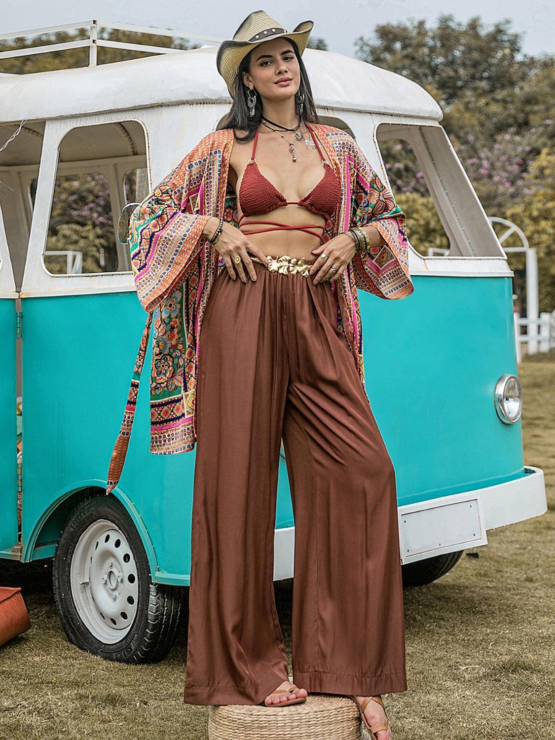 a woman in a bikini top and wide legged pants standing in front of a v