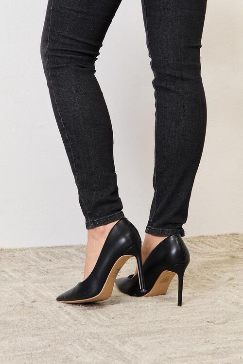 a woman wearing black high heels and skinny jeans