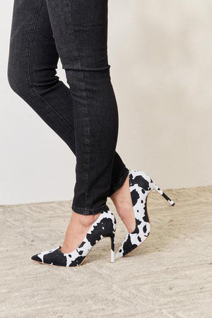 a woman wearing black and white shoes with a cow print on them