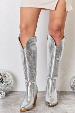 a close up of a person wearing silver cowboy boots