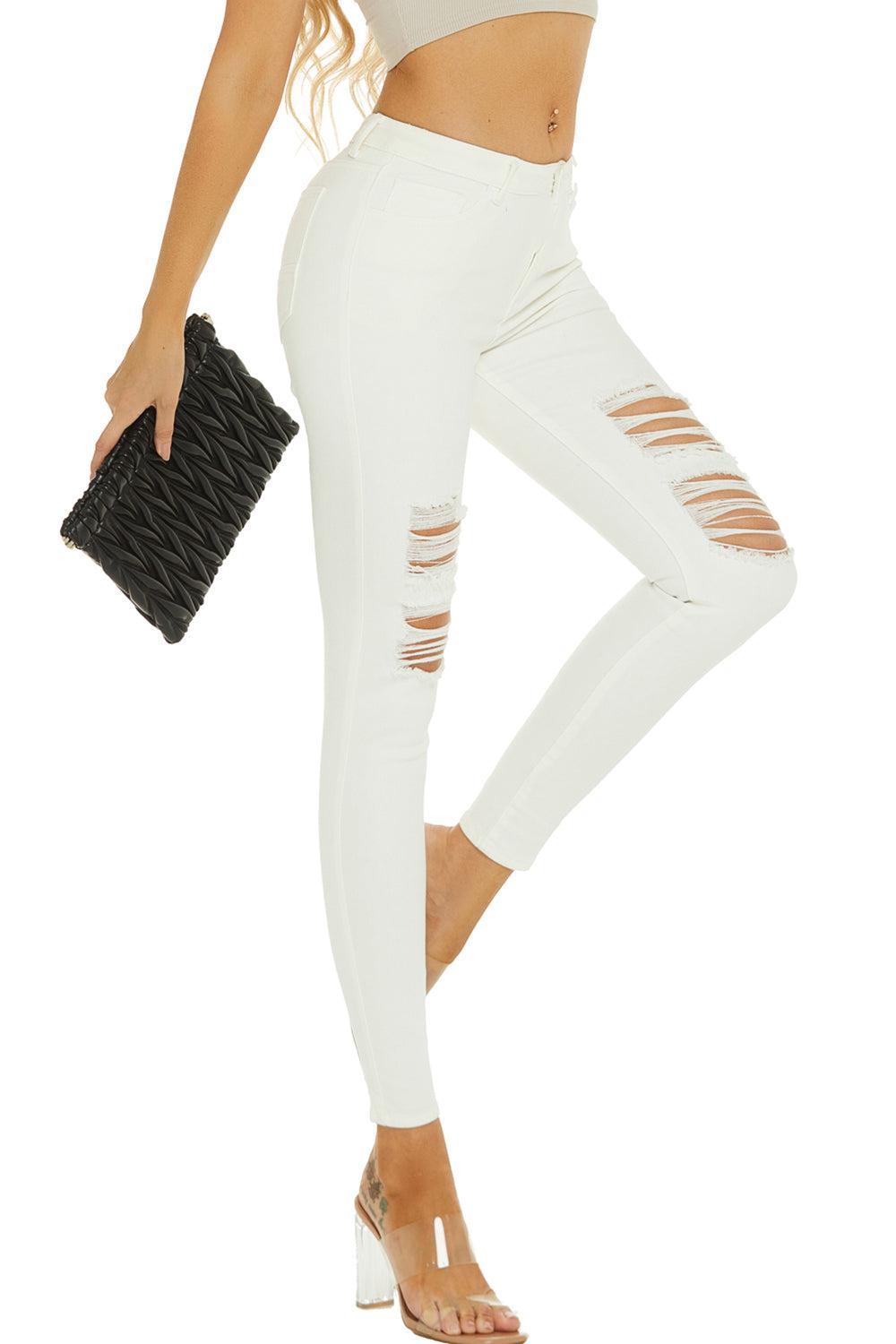 a woman in white ripped jeans holding a black purse