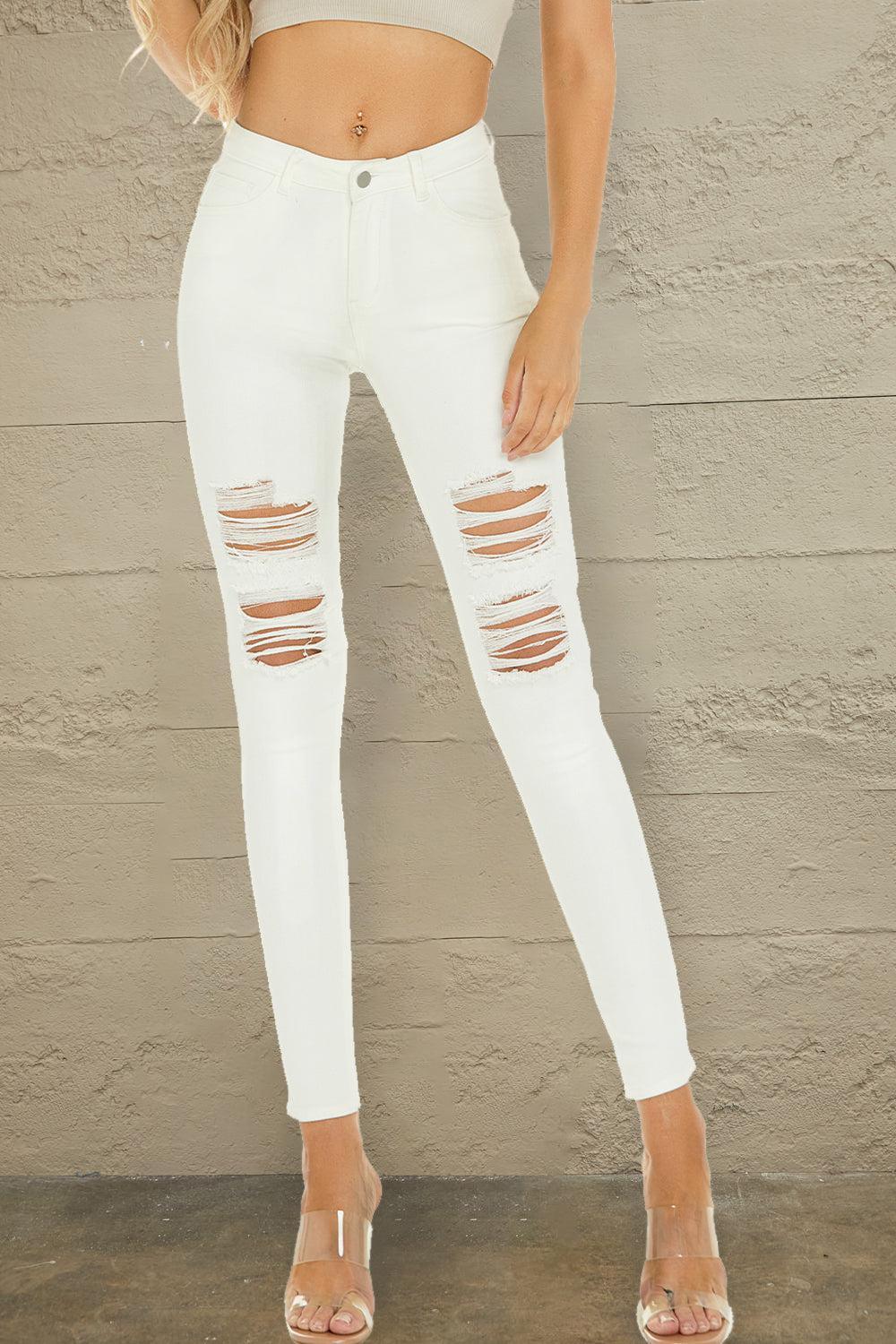 a woman wearing white ripped jeans and a crop top