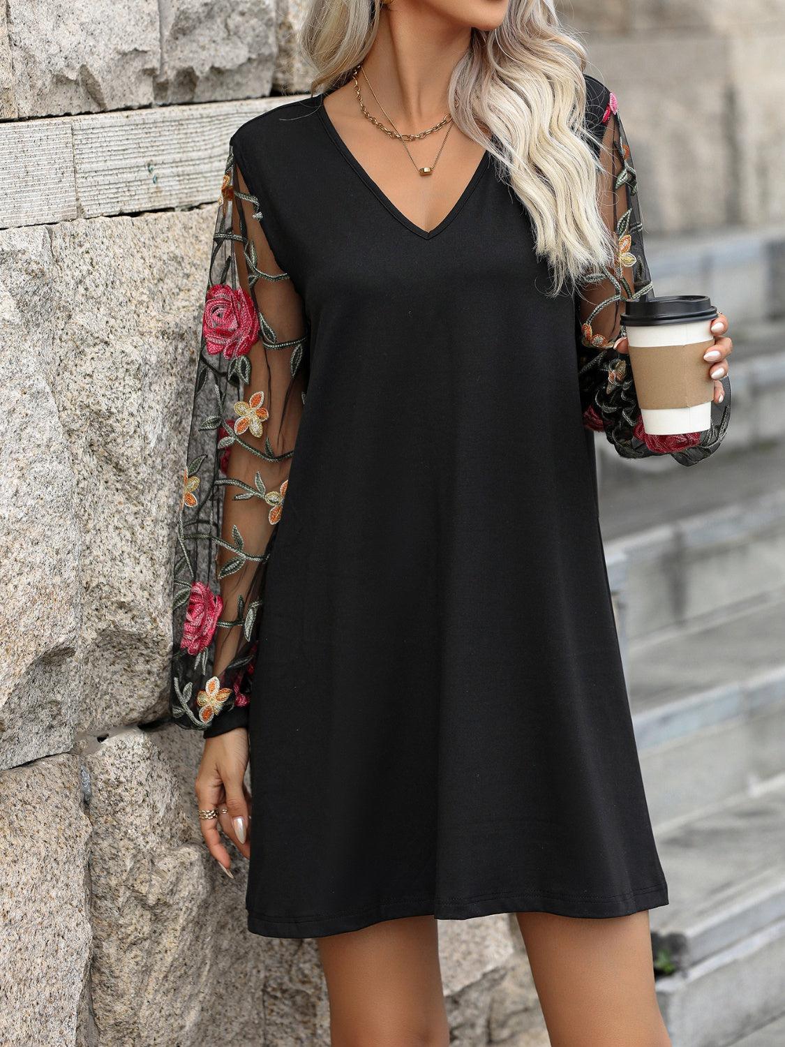 a woman holding a cup of coffee standing next to a stone wall